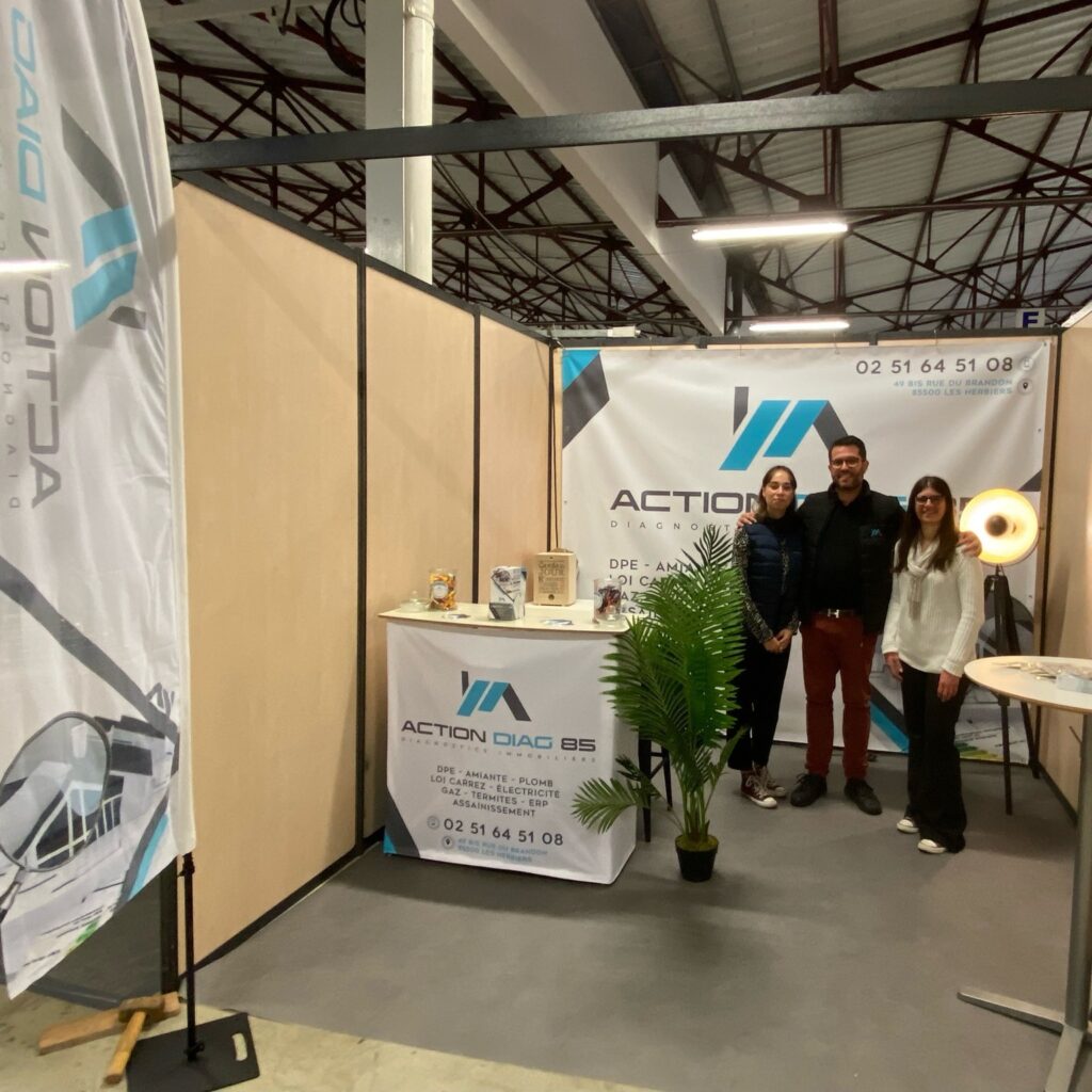 Visuel d'un stand d'exposition pour Action Diag BS, incluant un comptoir avec une bannière et un drapeau vertical, avec trois personnes debout à côté, et des informations sur les services de diagnostics et d'audits.