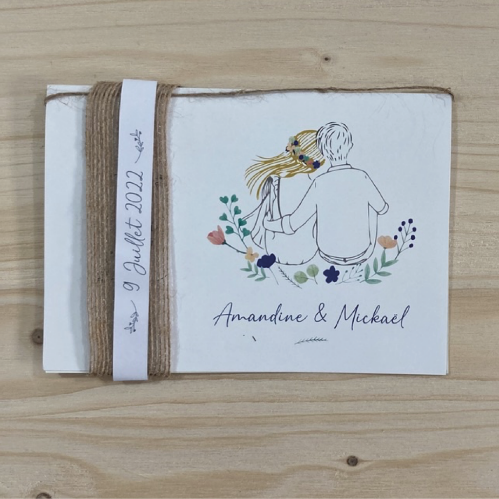 Visuel d'un faire-part de mariage pour Amandine et Mickaël, illustré avec un dessin d'un couple assis entouré de fleurs, avec une bande de tissu autour indiquant la date du mariage, le 9 juillet 2022.