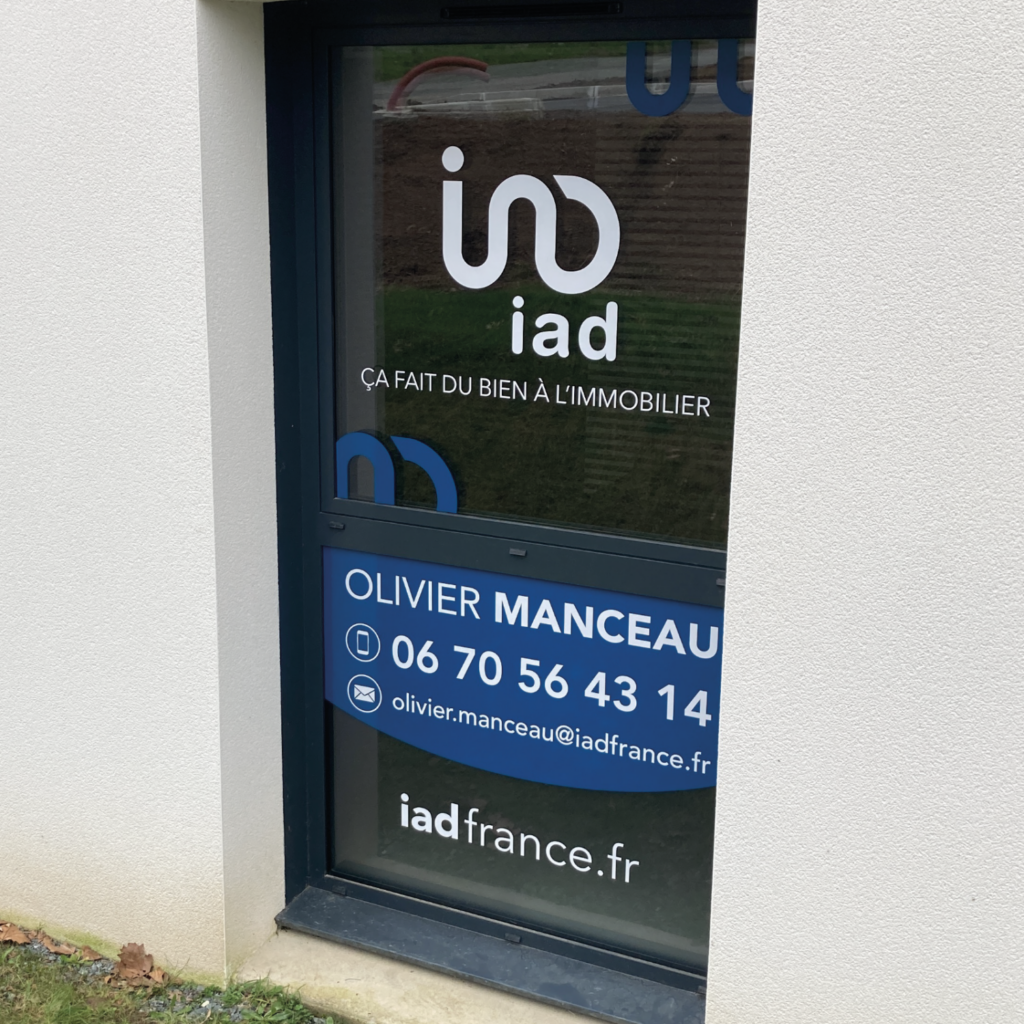 Visuel d'un adhésif pour vitrine d'une agence iad France, présentant le logo de l'entreprise et les informations de contact d'Olivier Manceau, un agent immobilier, incluant son numéro de téléphone et son adresse e-mail.