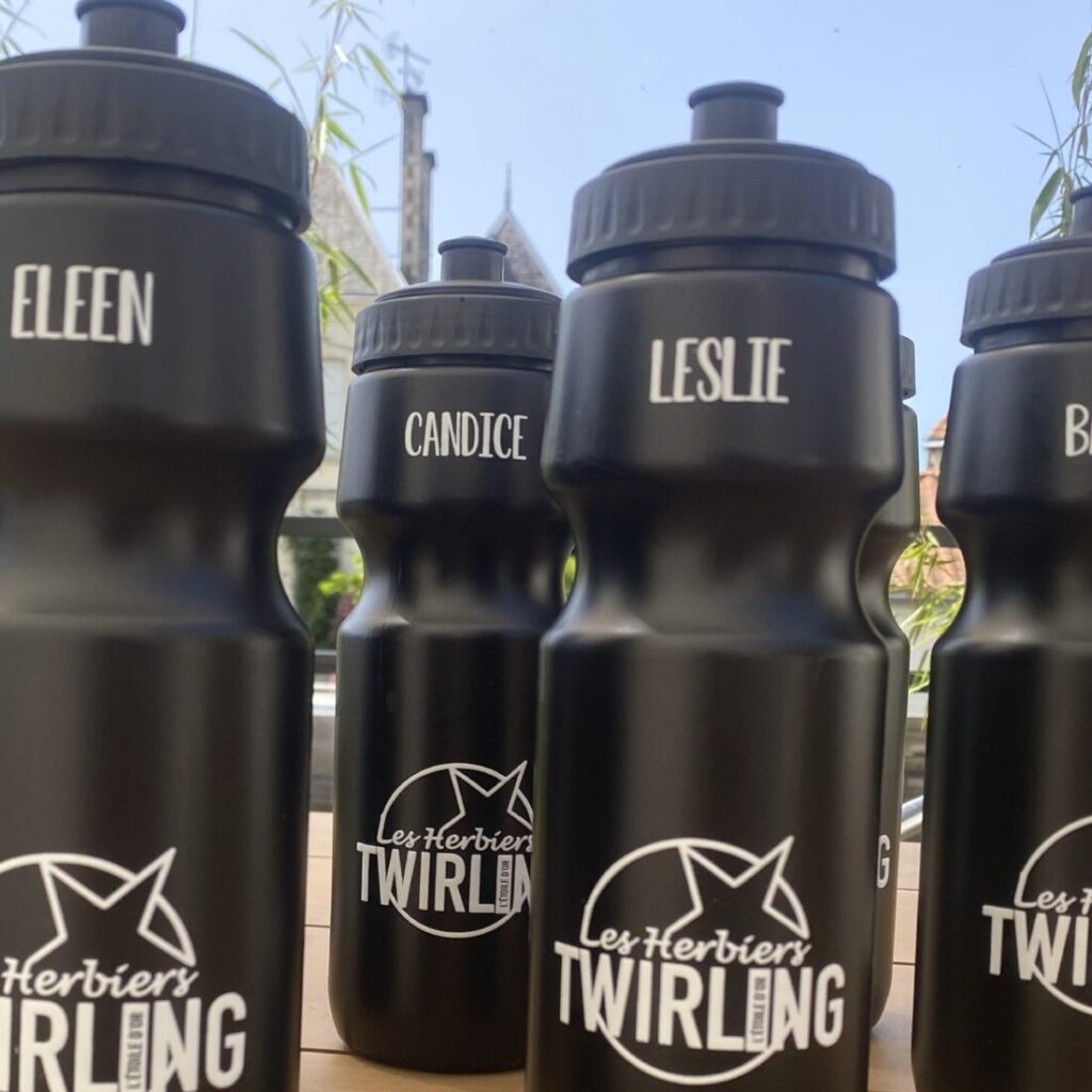 Gourdes noires personnalisées avec des noms individuels et le logo de 'Les Herbiers Twirling', illustrant des goodies personnalisés pour un événement ou une équipe.